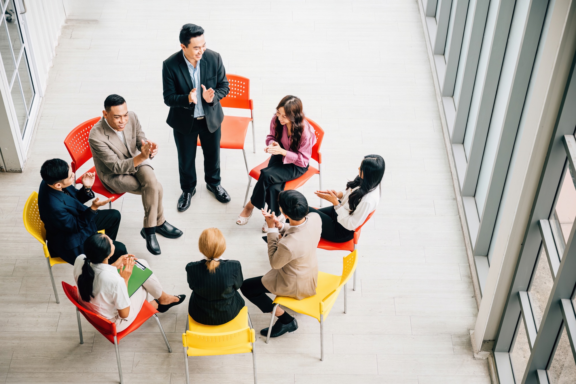 Top view captures a diverse group in a busy office, collaborating and engaged in discussions. A
